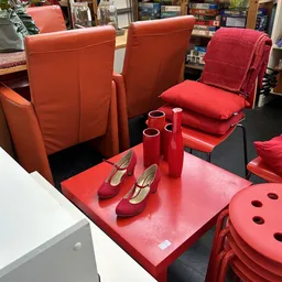 Uitgestalde dames-schoenen en rode accessoires op een rode tafel in de winkel