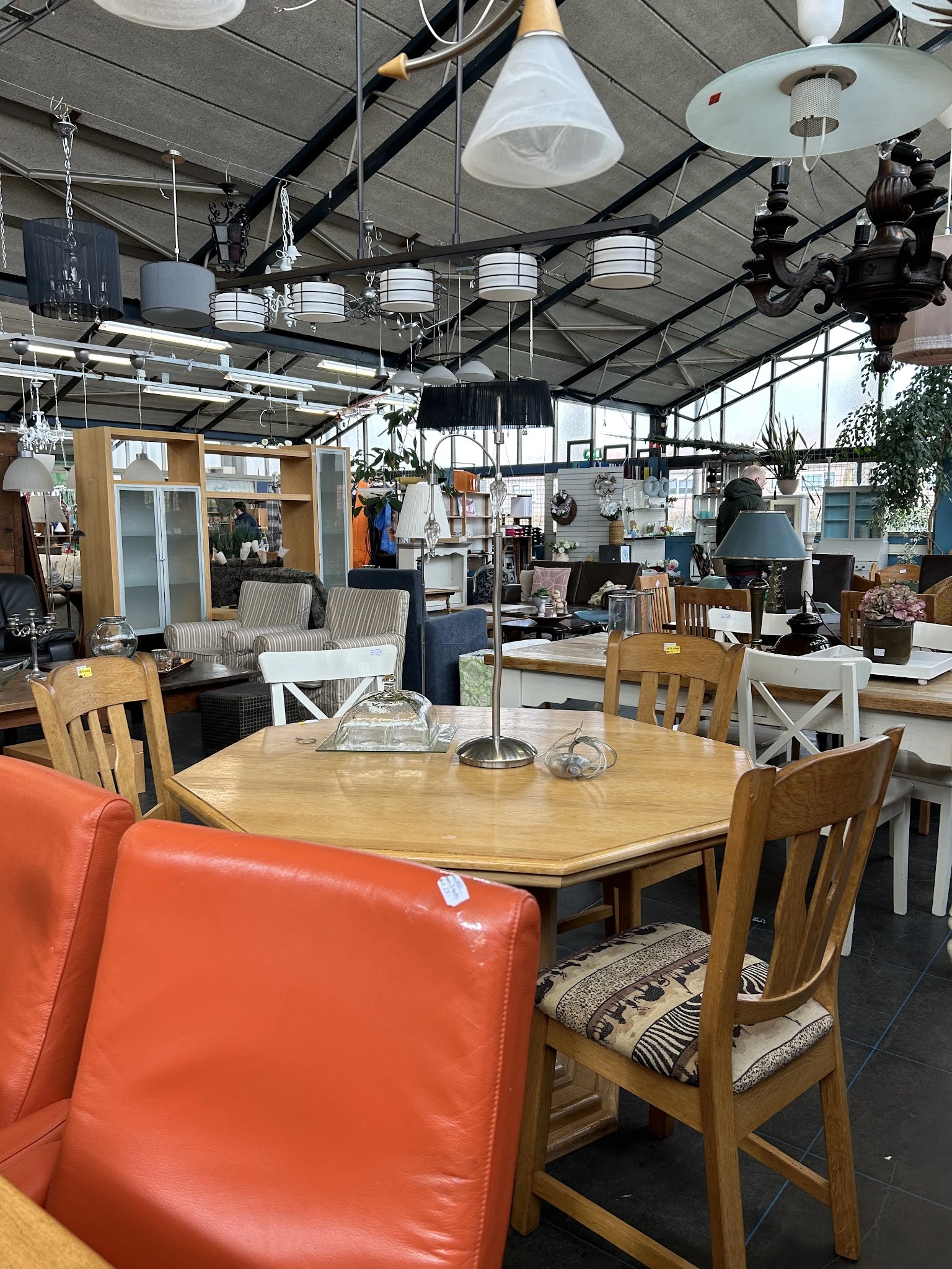 Winkelvloer met houten eettafel, stoelen en huisraad in een grote hal met industrieel plafond