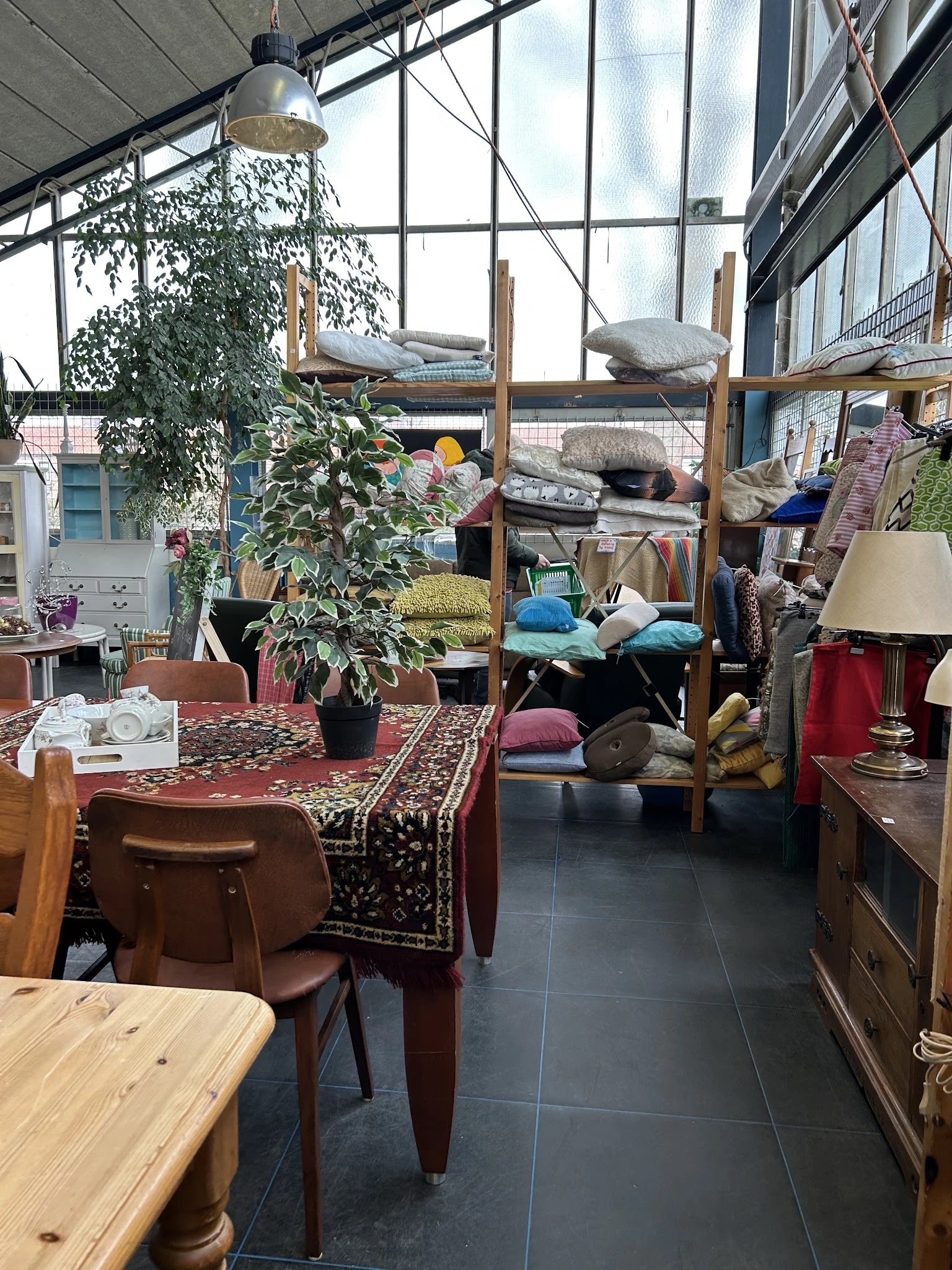 Winkelvloer met tafels, stoelen, meubels, kussens op stellingen, lampen en enkele planten
