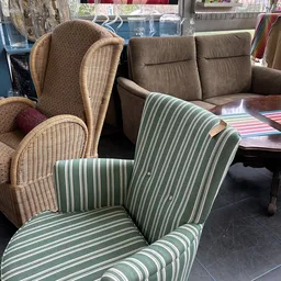 Fauteuils en stoelen met groen-wit gestreepte bekleding en rieten stoelen in uitstalling