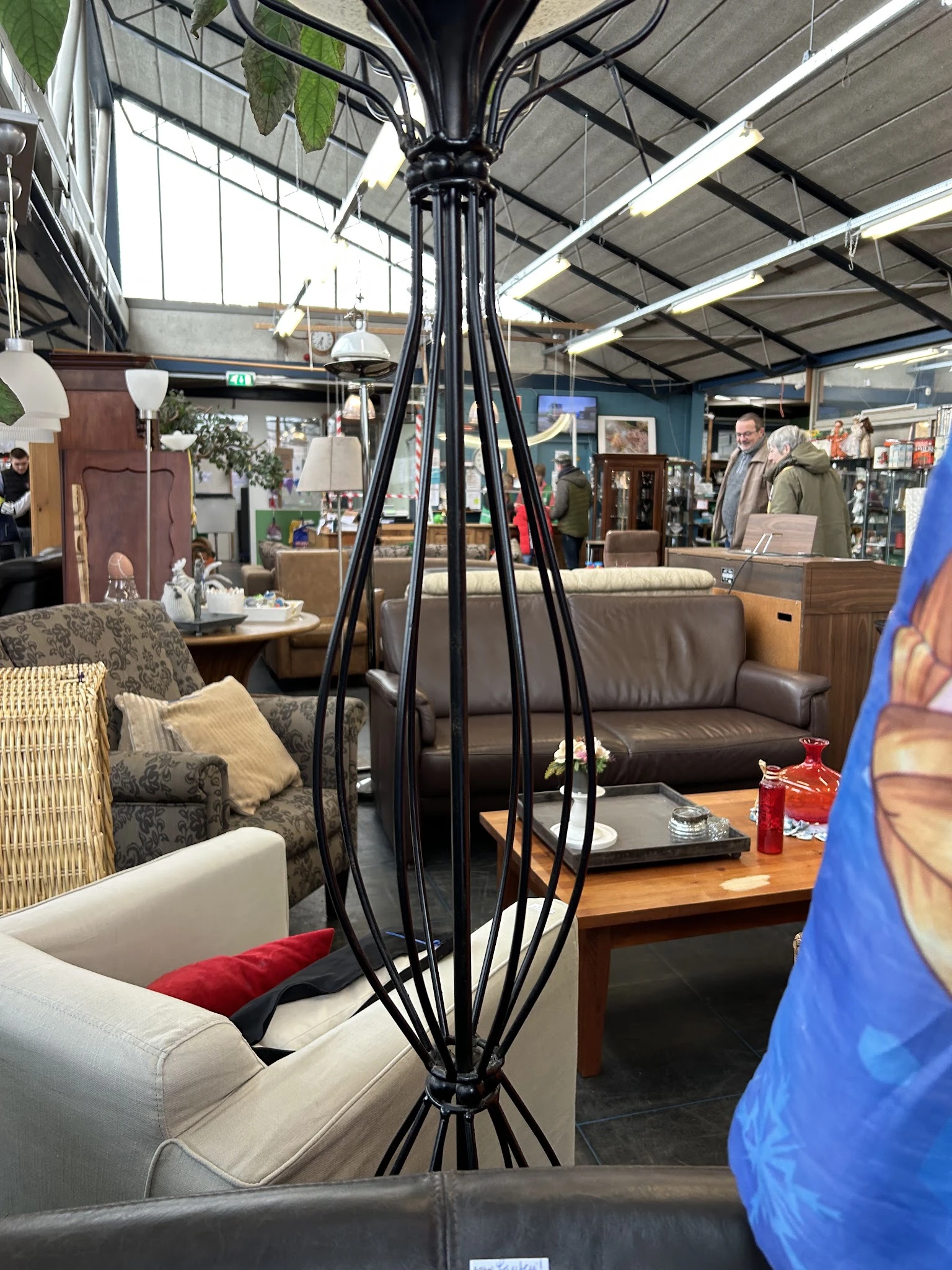 Winkelvloer met diverse meubels: zithoeken, banken, stoelen en decoratieve items zoals een zwarte staande lamp op voorgrond