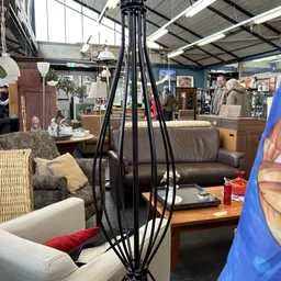Winkelvloer met diverse meubels: zithoeken, banken, stoelen en decoratieve items zoals een zwarte staande lamp op voorgrond