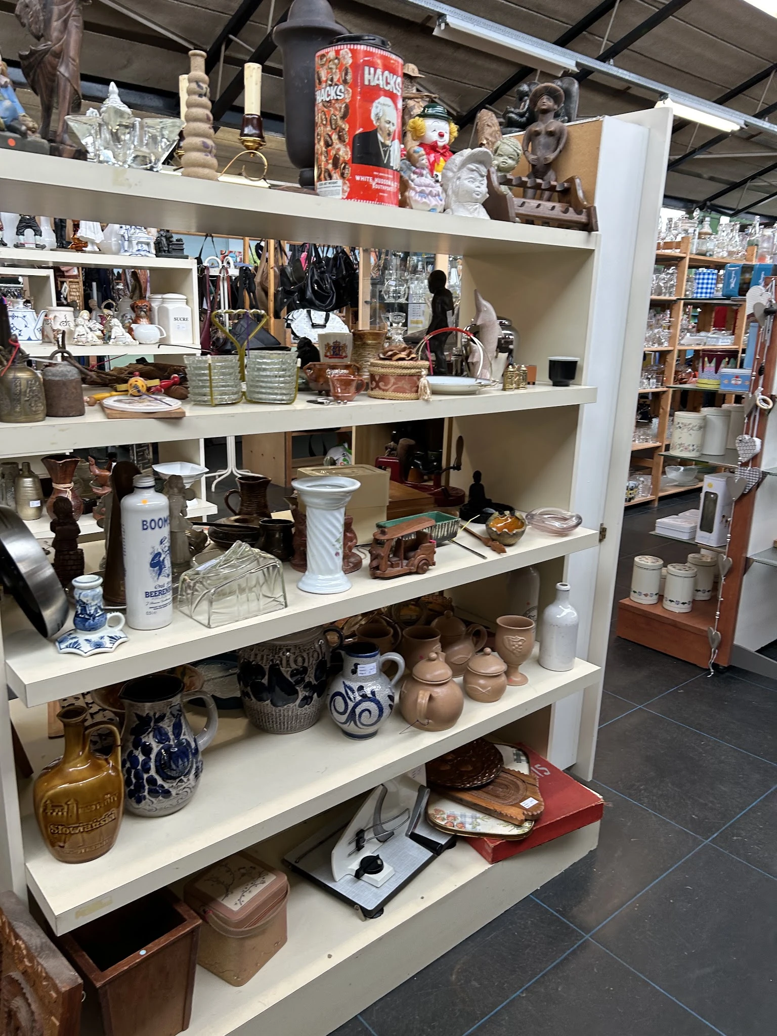 Stellingen met diverse huishoudelijke artikelen, servies, vazen en decoratiespullen in de winkel