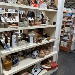 Stellingen met diverse huishoudelijke artikelen, servies, vazen en decoratiespullen in de winkel