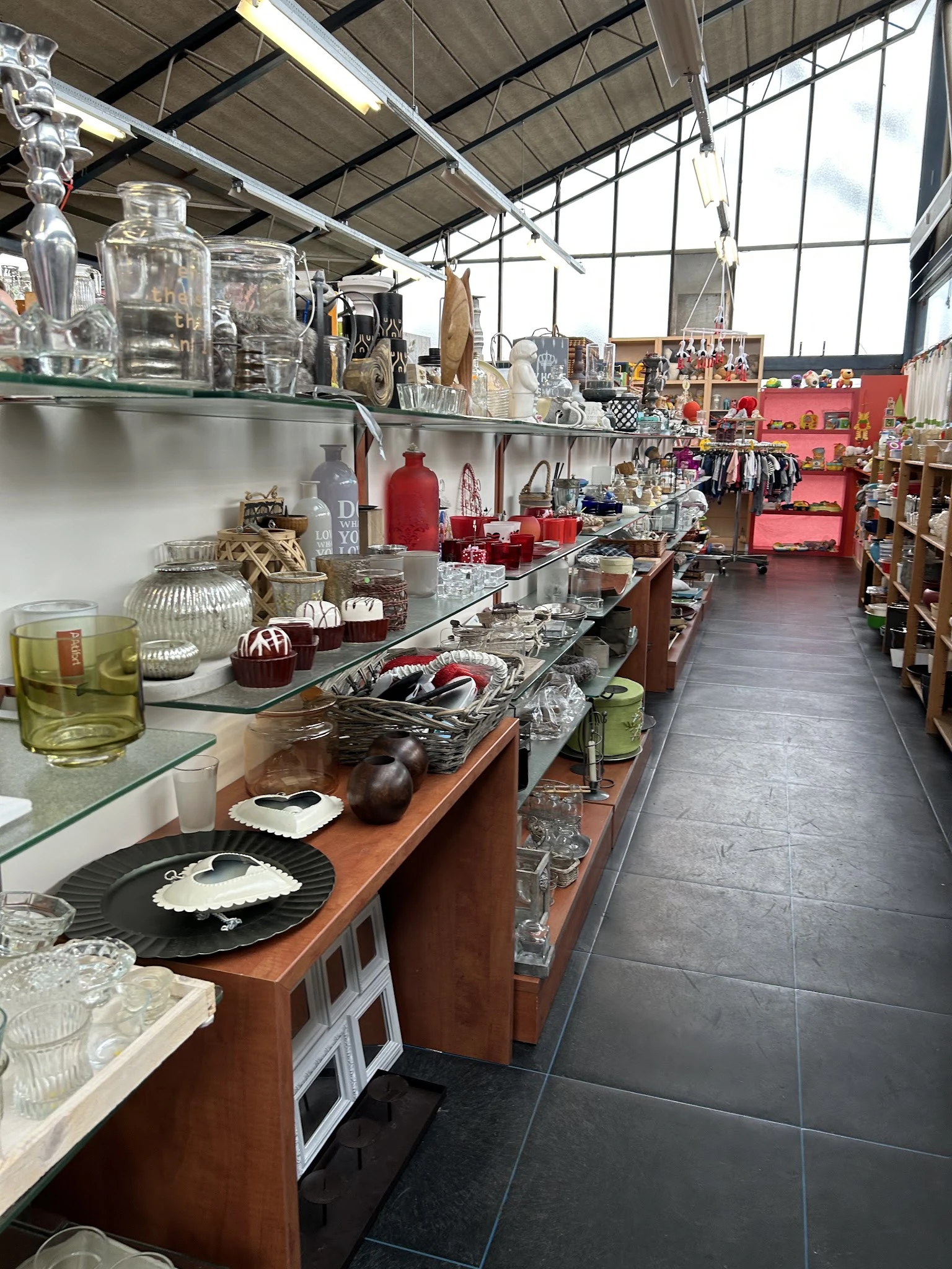 Uitgestalde huishoudelijke artikelen en decoratie op tafels en schappen in de kringloopwinkel