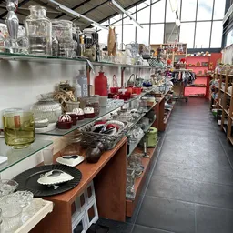 Uitgestalde huishoudelijke artikelen en decoratie op tafels en schappen in de kringloopwinkel