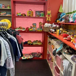 Rode stellingen met speelgoed, knuffels en huishoudartikelen, links daarnaast kleding aan hangers