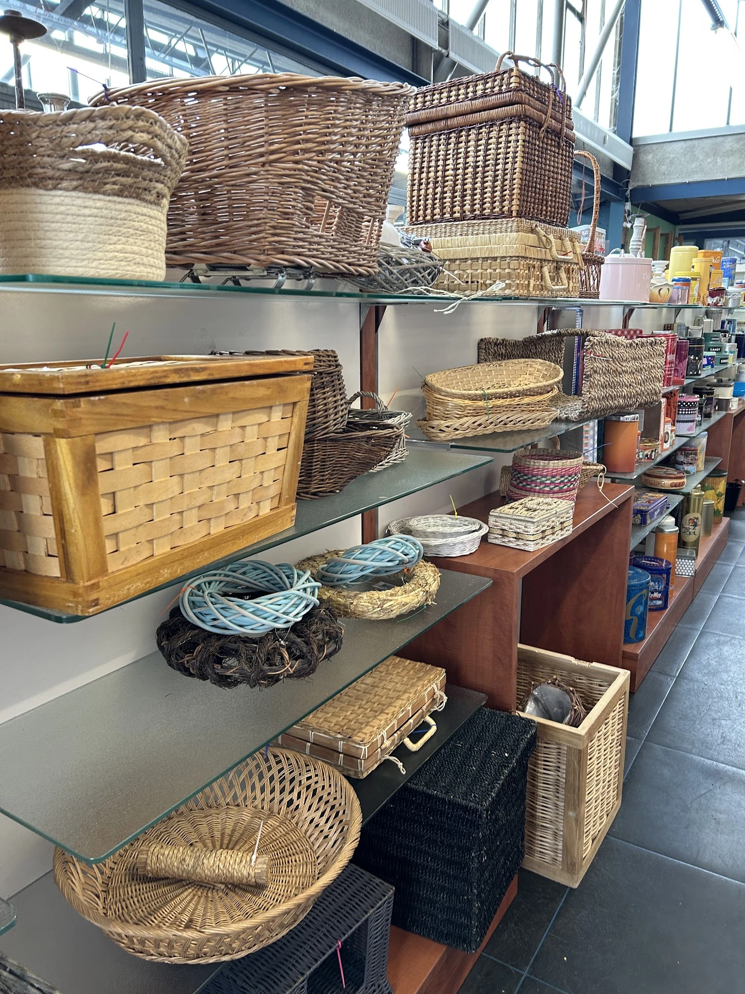 Schappen met diverse rieten manden, houten kratten en huishoudelijke accessoires