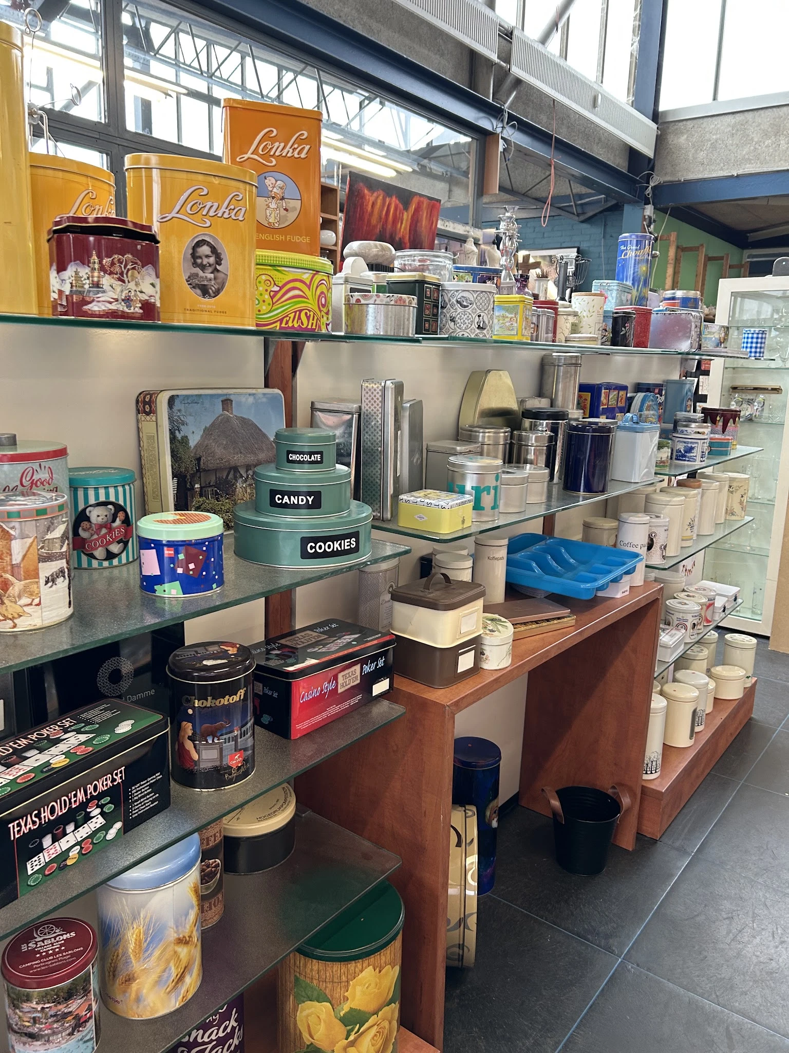 Uitgestalde huishoudelijke artikelen en decoratieve items op planken en toonbank in kringloopwinkel