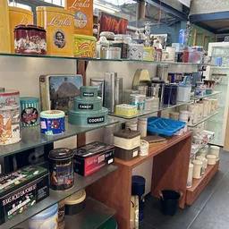 Uitgestalde huishoudelijke artikelen en decoratieve items op planken en toonbank in kringloopwinkel