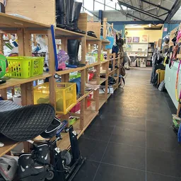 Winkelvloer met houten stellingen, gele en groene opbergkratten, fietsen en diverse spullen in een kringloopwinkel