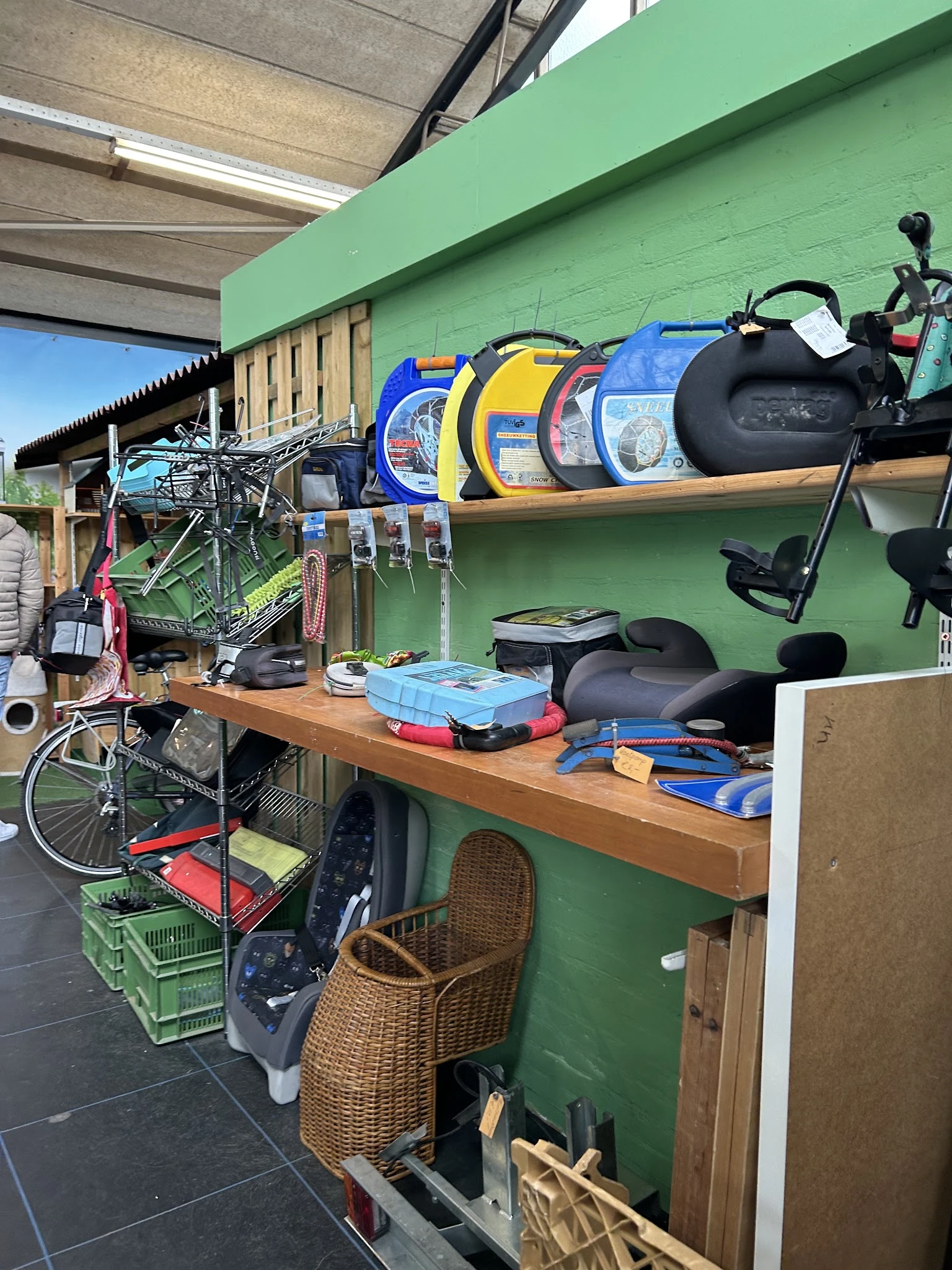Werkbank met uitgestalde spullen: fiets, sportrugtassen, fietszadels, toolboxen en ander tweedehandsaanbod