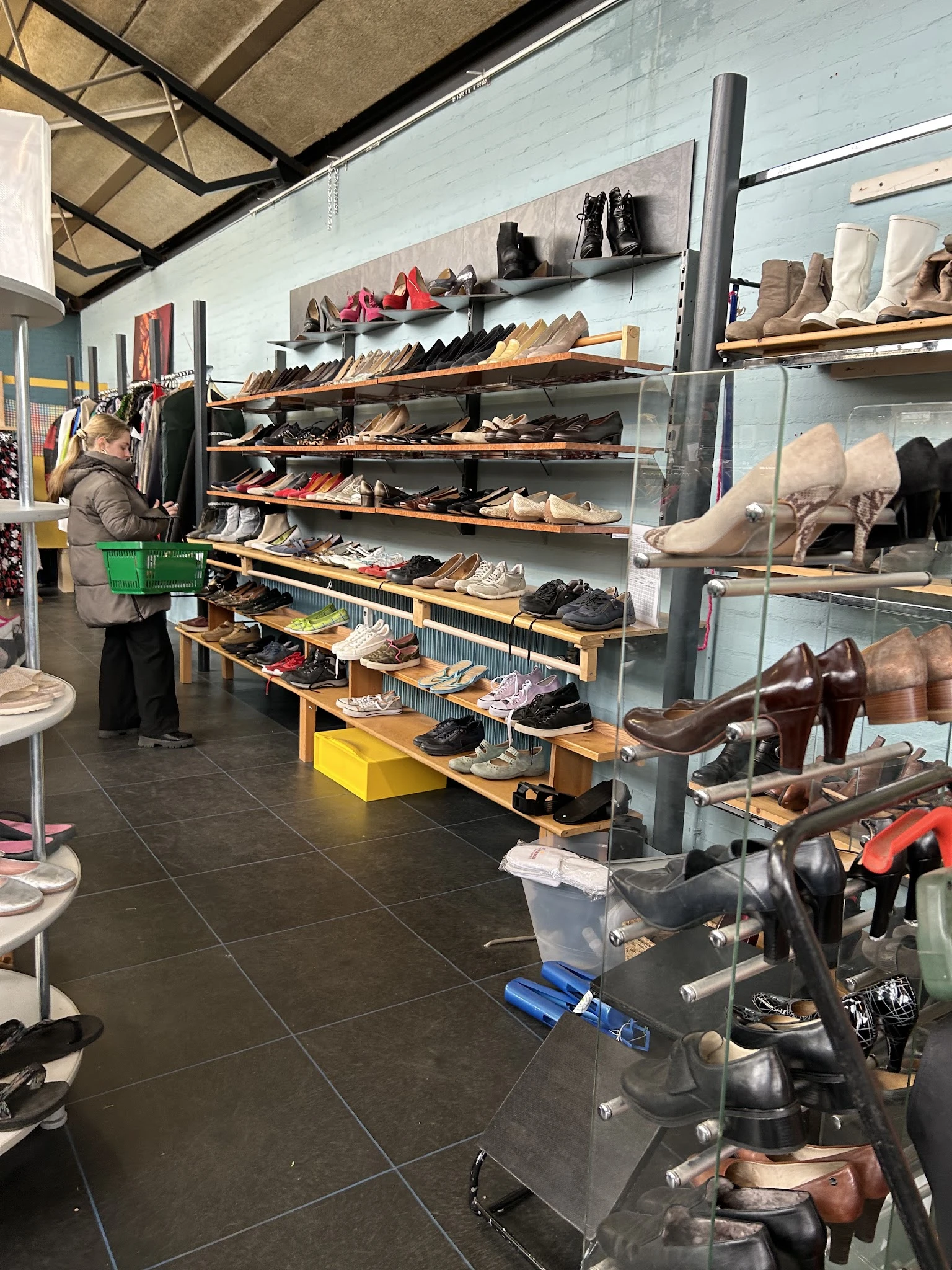 Uitgestalde schoenen op houten stellingen en in vitrinekastjes in een kringloopwinkel