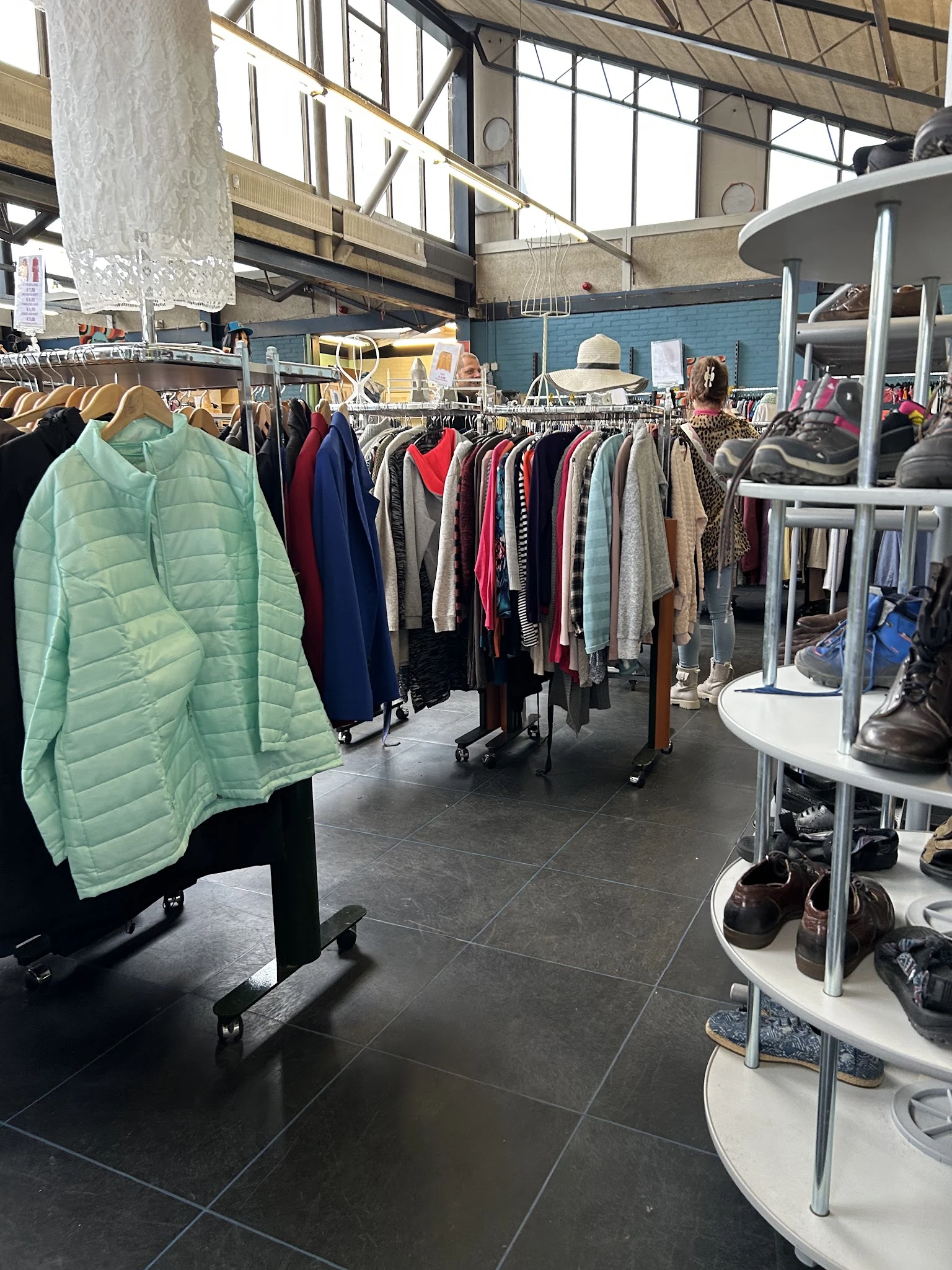 Rekken met tweedehands kleding, waaronder jassen, truien en andere kledingstukken in verschillende kleuren