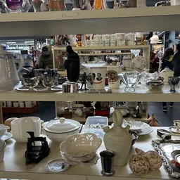 Tweedehands serviesgoed, kopjes, schalen en glazen op uitstalling in de winkel