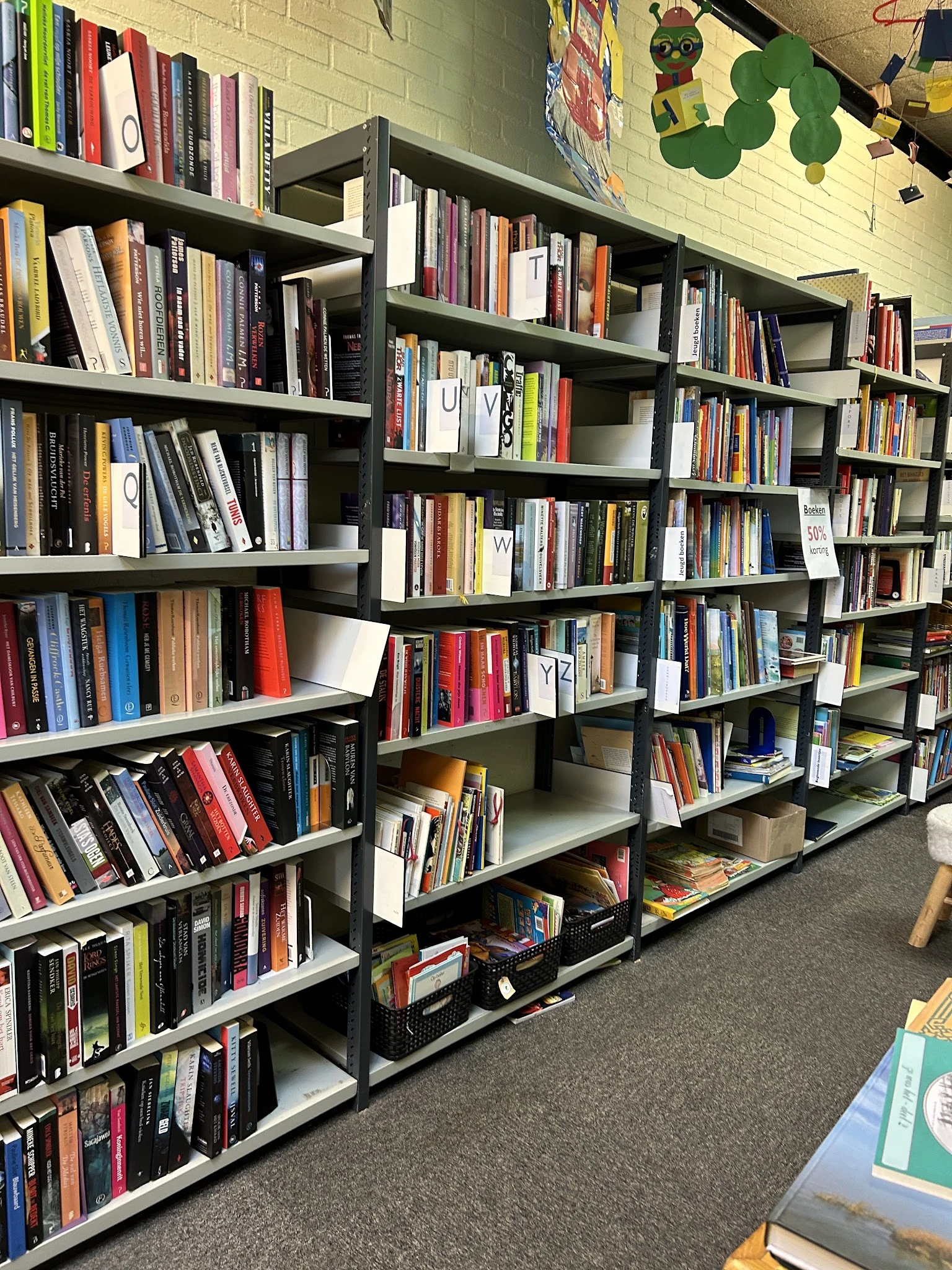 Boekenkasten vol met tweedehands boeken in verschillende genres en kleuren
