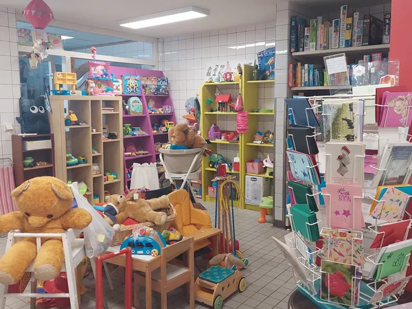 Kinderafdeling in kringloopwinkel met speelgoed, knuffels, boeken en kleurrijke stellingen vol spullen