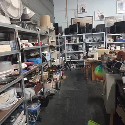 Winkelinterieur met metalen stellingen vol spullen, dozen en diverse gebruiksartikelen
