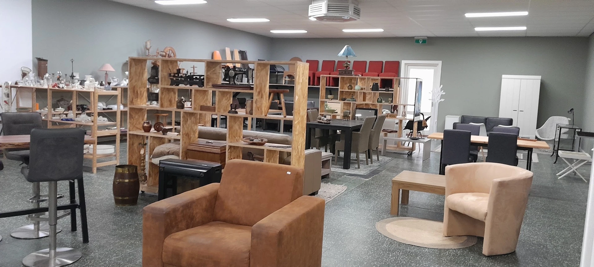 Winkelvloer met bruine lederen fauteuil, houten kasten en stellingen met huishoudelijke spullen en decoraties
