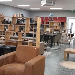 Winkelvloer met bruine lederen fauteuil, houten kasten en stellingen met huishoudelijke spullen en decoraties