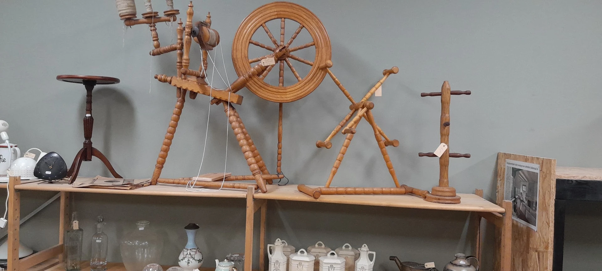 Houten spinwielen, spinnewiel en ander antiek huishoudelijk gereedschap op een houten stellage