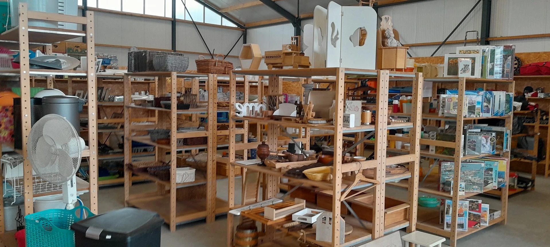 Winkelvloer met houten stellingen vol met huishoudelijke artikelen, servies en diverse spullen in een kringloopwinkel