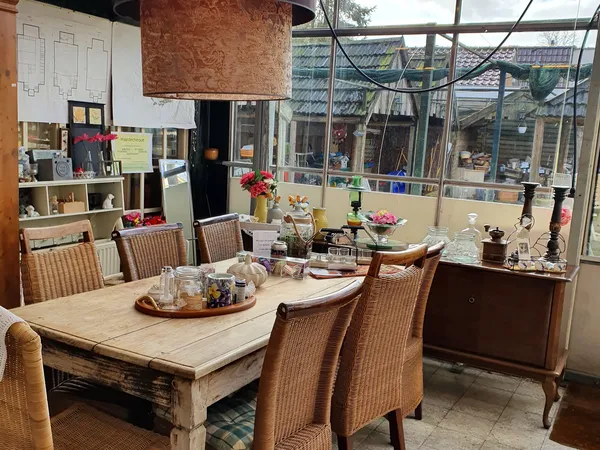 Woonkamer interieur met houten eettafel, rieten stoelen en grote ramen met uitzicht op straat