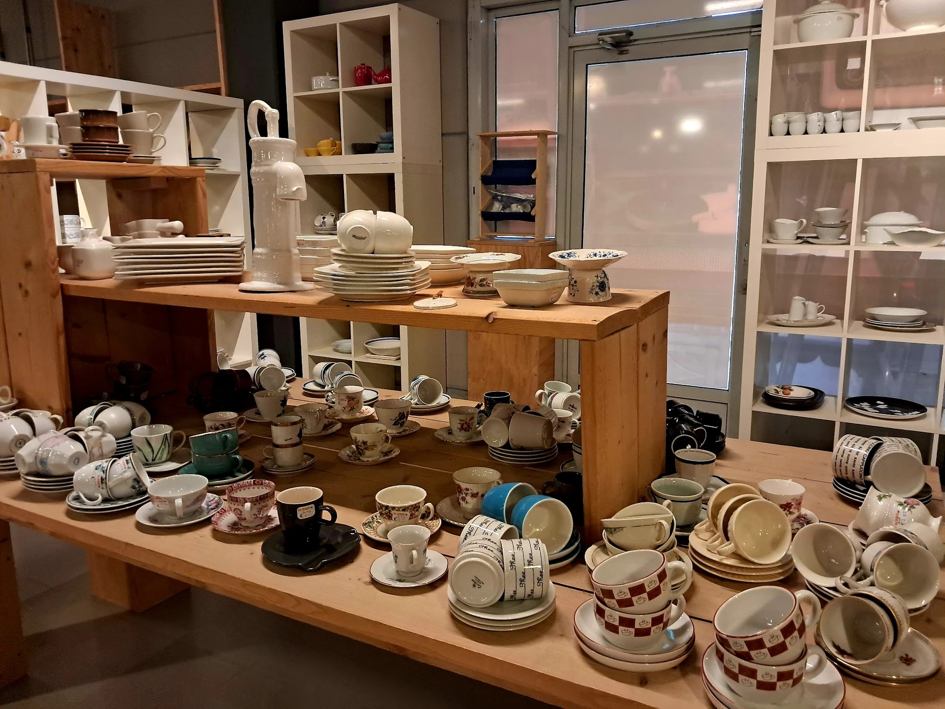 Uitgestalde serviesgoed en kopjes op houten tafels in de winkel