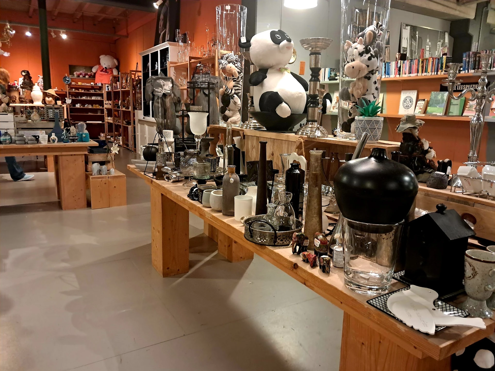Winkelvloer met houten display-tafels vol decoratieve objecten, zwart-witte poppen en glaswerk