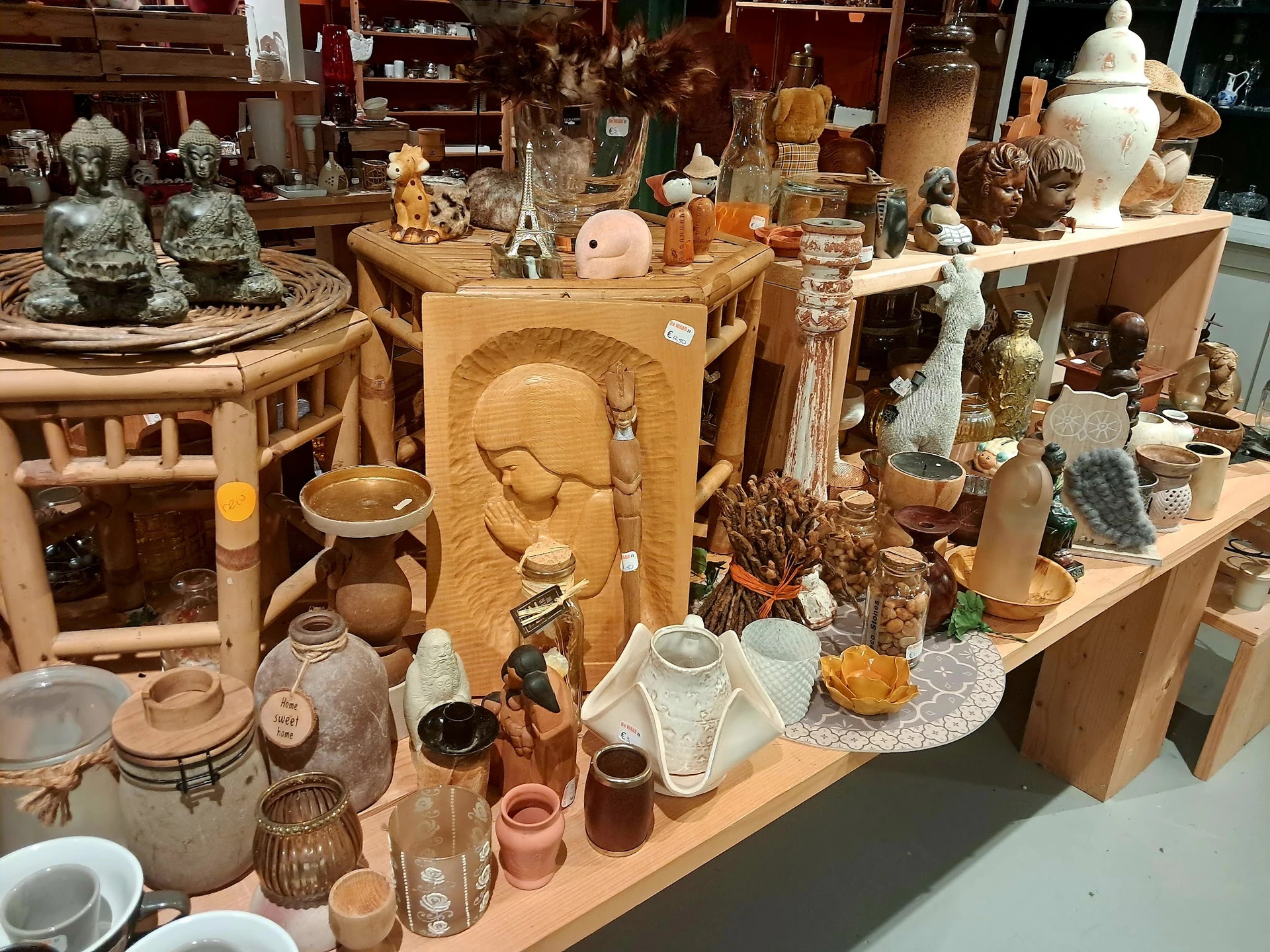 Uitgestalde tweedehands decoratieartikelen, beeldjes, vazen en houten snijwerk op houten stellingen