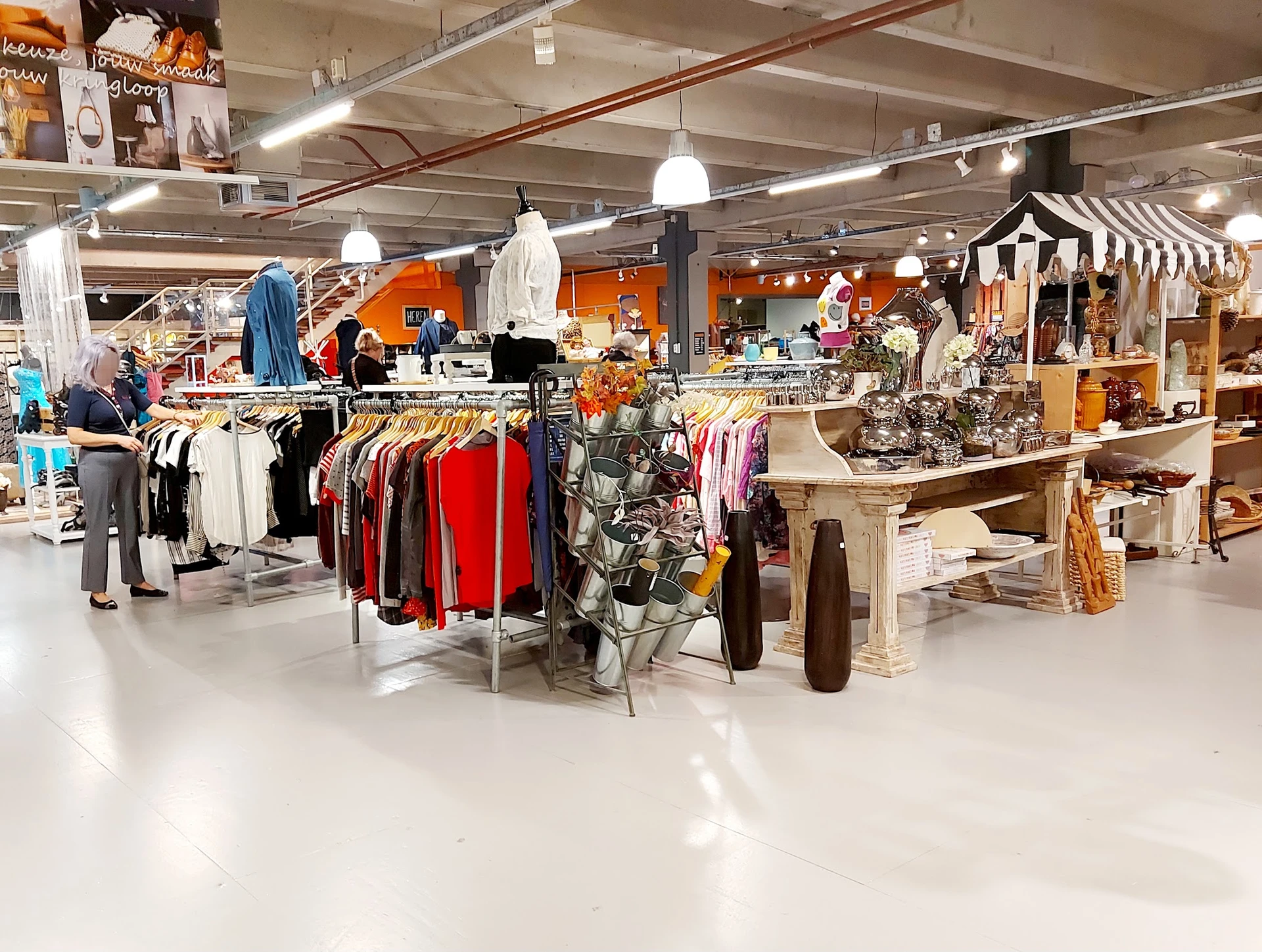Winkelvloer met kledingrekken, toonbanken en diverse artikelen verspreid door de winkelruimte