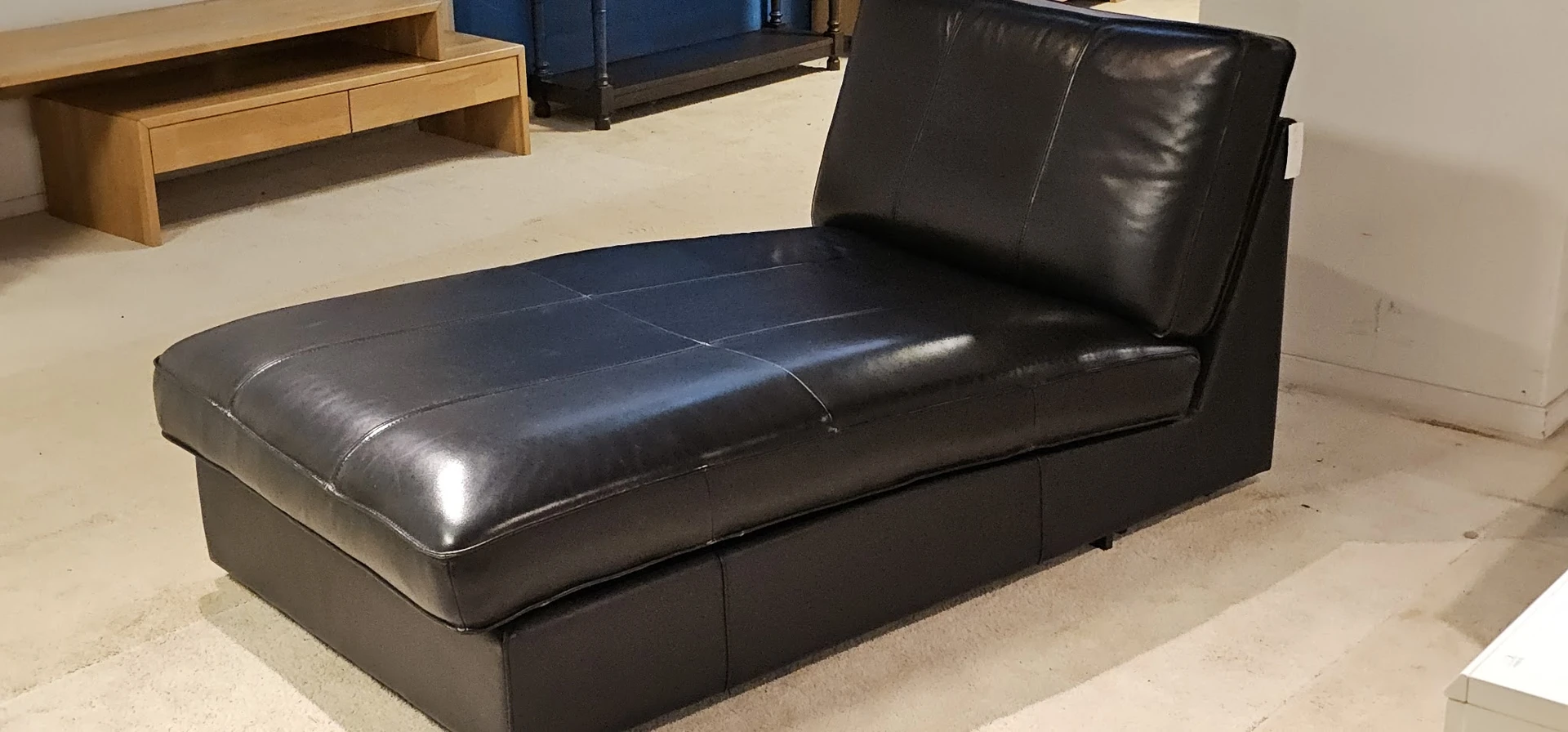 Zwarte leren chaise longue of loungebank met opklapbare rugleuning in een winkelinterieur