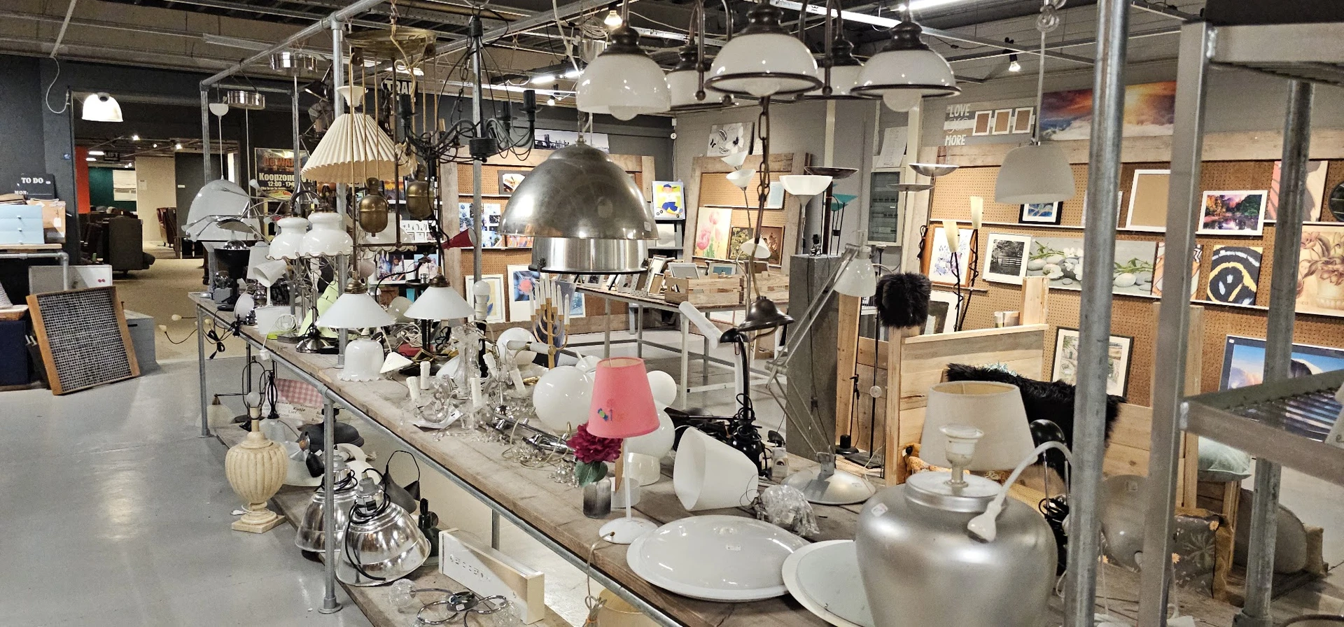 Uitgestalde huishoudelijke artikelen: lampen, servies, bloemen en decoratieve items op een toonbank
