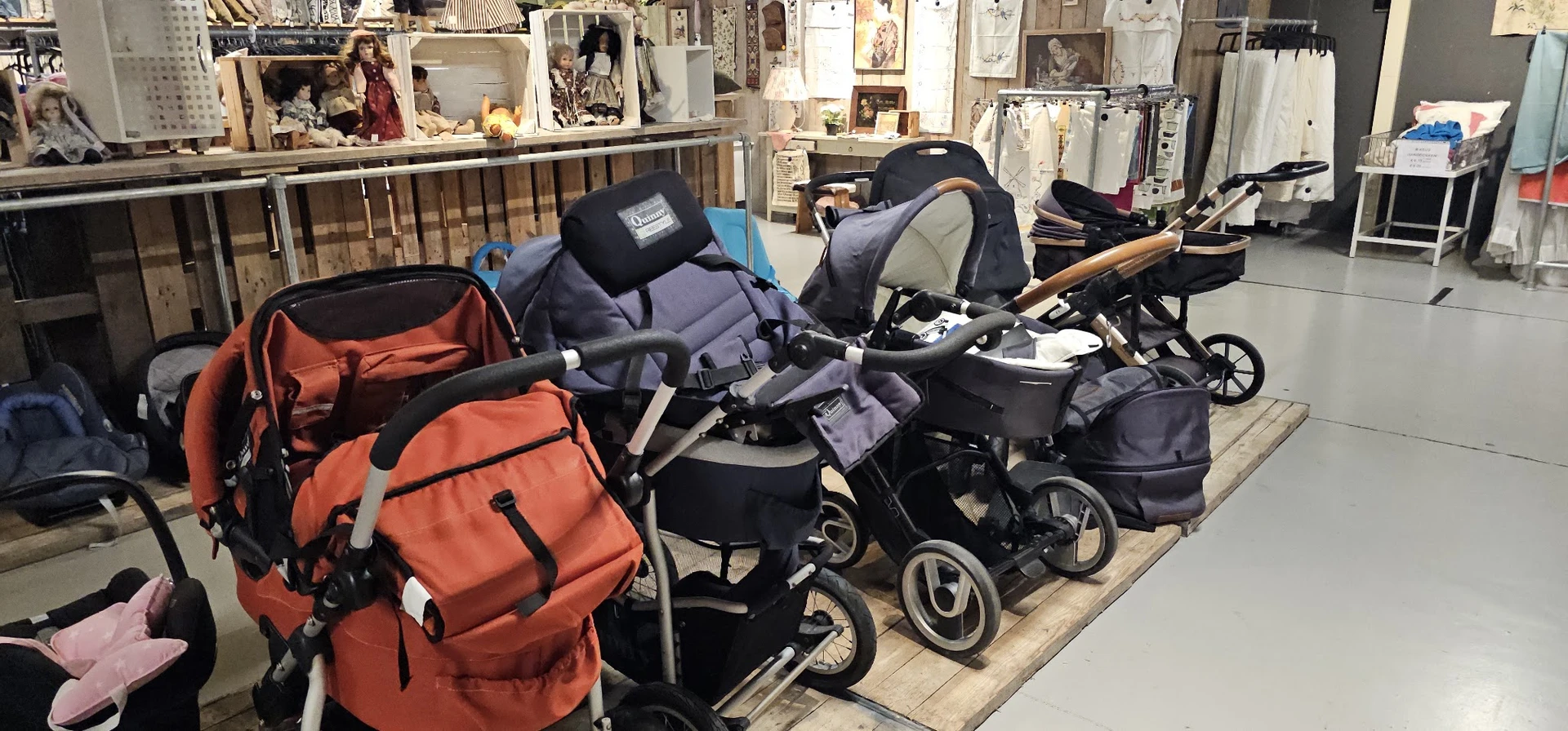 Uitgestalde kinderwagens en buggy's in verschillende kleuren in een kringloopwinkel