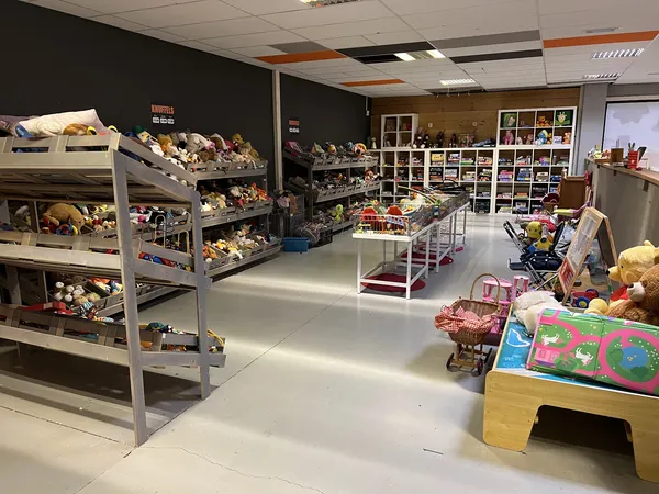Winkelvloer met stellingen vol speelgoed, poppen en knuffels in een kringloopwinkel