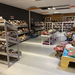 Winkelvloer met speelgoed en knuffels op stellingen, tafels en in dozen