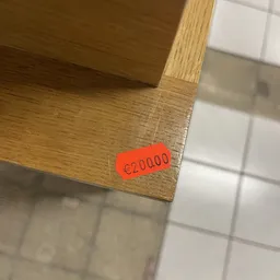 Rode prijssticker met €20000 op houten meubel