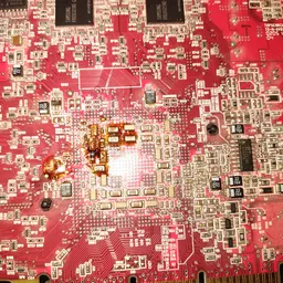 Close-up van een rode printplaat met elektronische componenten en soldeerwerk