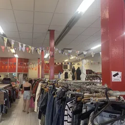 Winkelvloer met kledingrekken, rode zuilen en decoratie in een kringloopwinkel