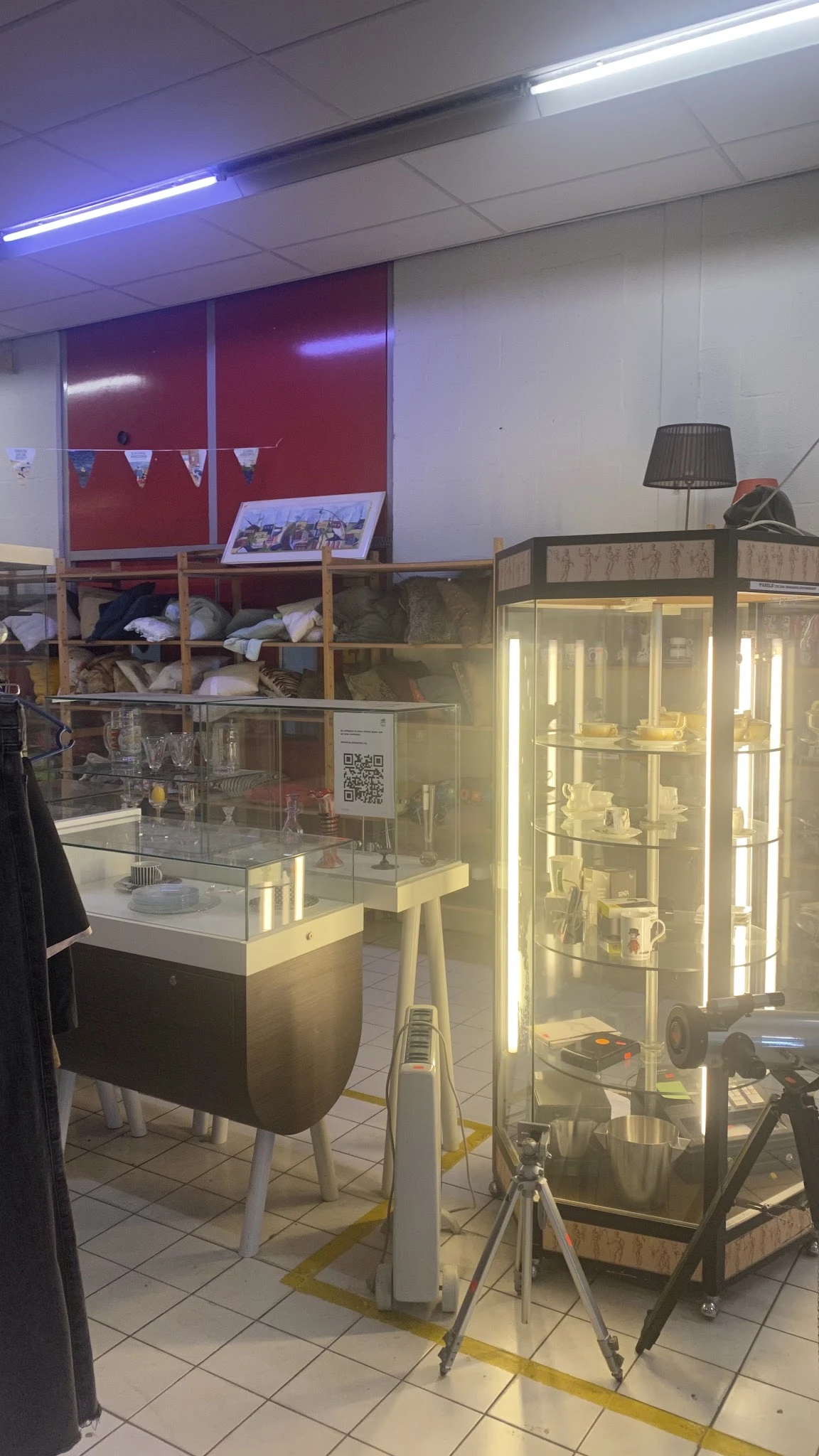 Verlichte vitrinekasten met serviesgoed en huishoudelijke artikelen in de kringloopwinkel