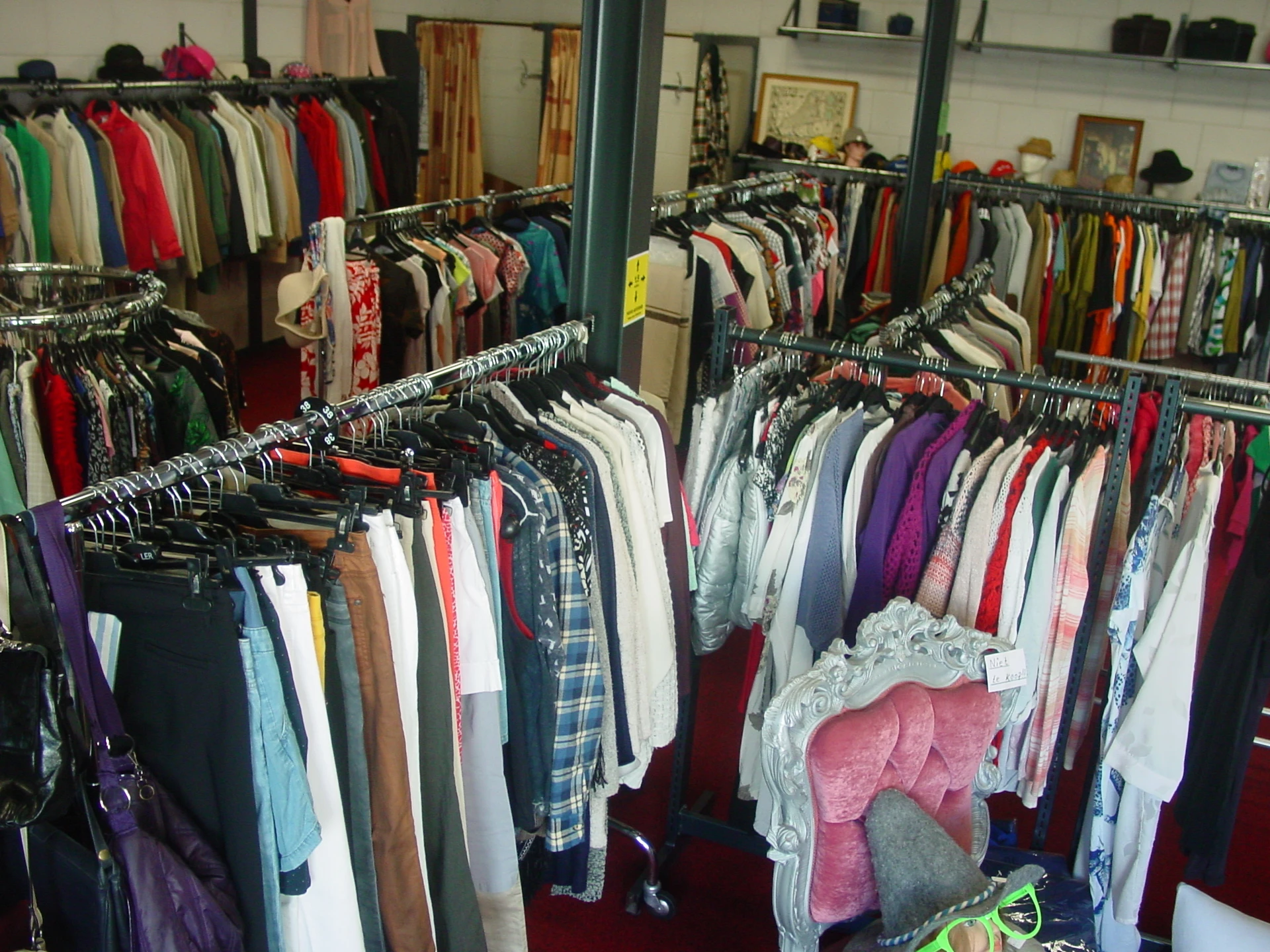 Rekken met tweedehands kleding in verschillende kleuren en stijlen