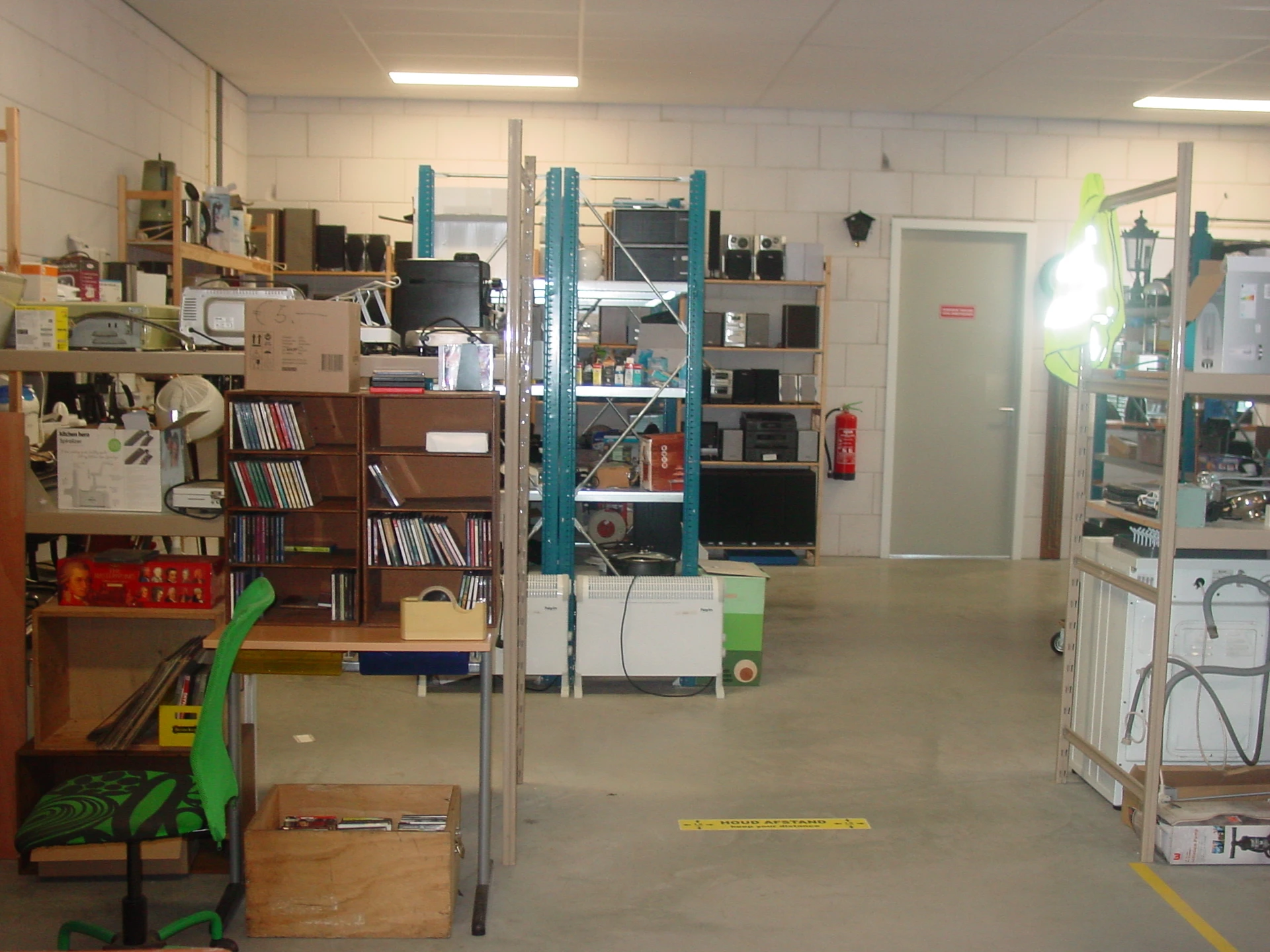 Winkelvloer met stellingen, boekenkasten, dozen en diverse spullen in een kringloopwinkel