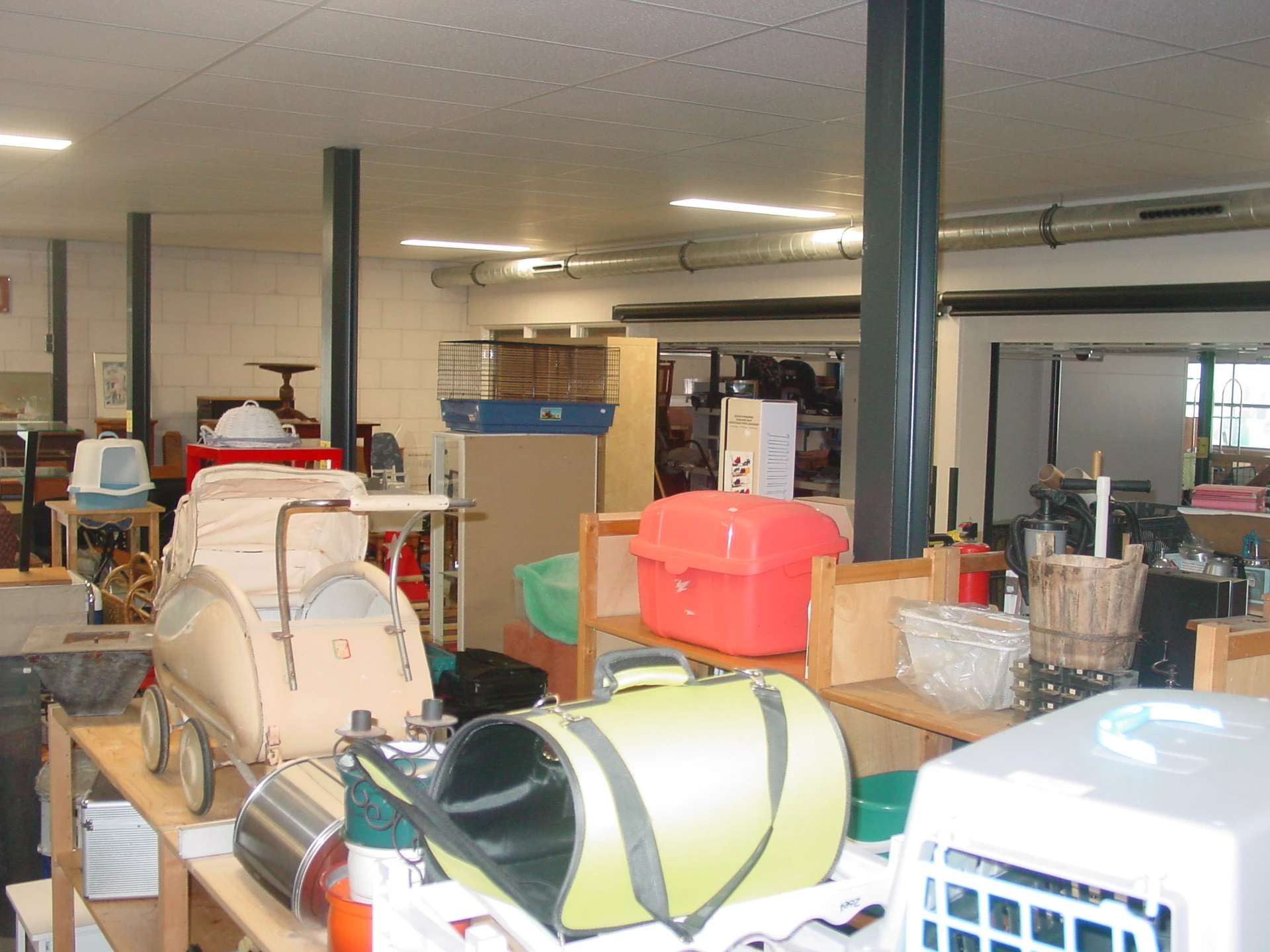 Winkelinterieur met stellingen vol diverse tweedehandsartikelen zoals kinderwagens, tassen en huishoudspullen