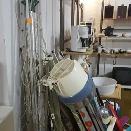 Werkruimte met opgehangen kabels, emmers en diverse spullen op rekken tegen de muur