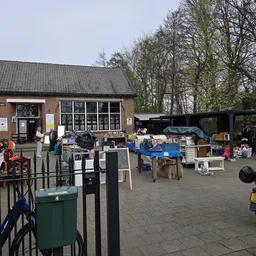 Buitenterrein met diverse uitgestalde tweedehands spullen, meubilair en goederen bij een kringloopwinkel