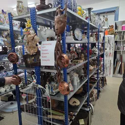 Blauwe stellingen met decoratieve artikelen, beeldjes, servies en huishoudspullen in een kringloopwinkel