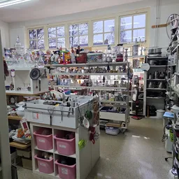 Overzicht van de winkelvloer met stellingen, werkblad en diverse uitgestalde artikelen in een kringloopwinkel