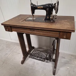 Antieke naaimachine met houten tafel en zwarte metalen voetbediening