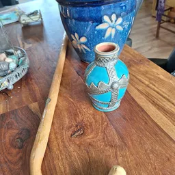 Turquoise decoratief potje met zilveren details op houten tafel