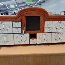 Vintage houten kruidenkast met tien glazen potten met draaideksels, gelabeld met verschillende kruiden- en specerijennamen